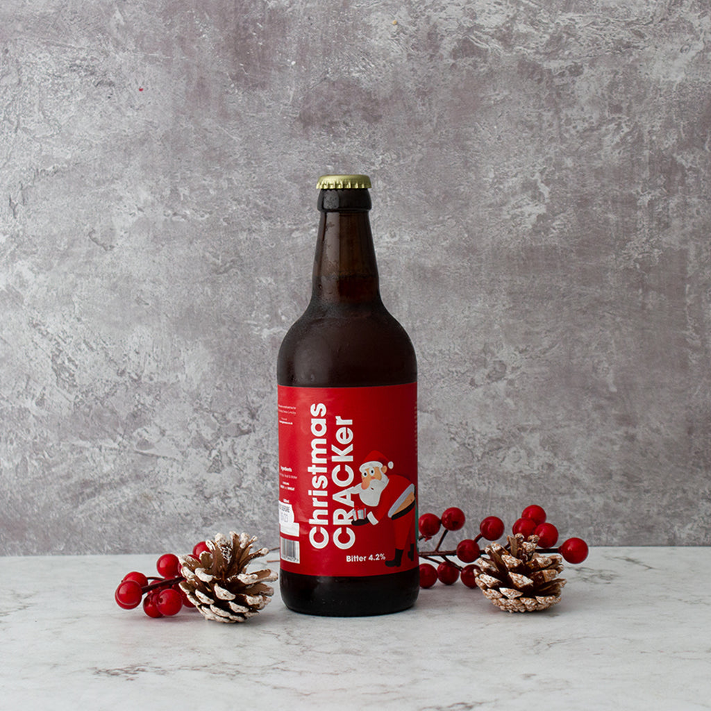 “Christmas Cracker” Christmas beer bottle styled with pine cones and red berries.