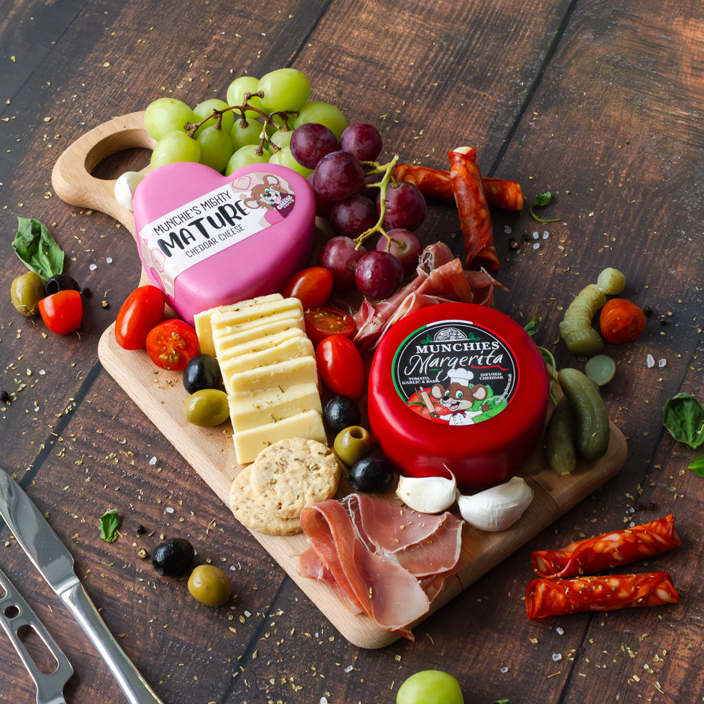 Cheese sharing board with Mighty Mature Cheddar, flavoured cheddar, crackers, cured meat, grapes and savoury snacks.