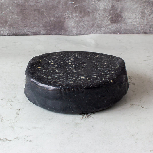 Chuckling Cheese black wax-coated cheese wheel on a white surface