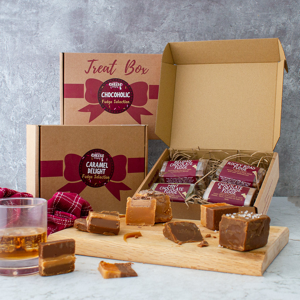 Chuckling Cheese Treat Box with fudge pieces, confectionery packets and a drink on a wooden board