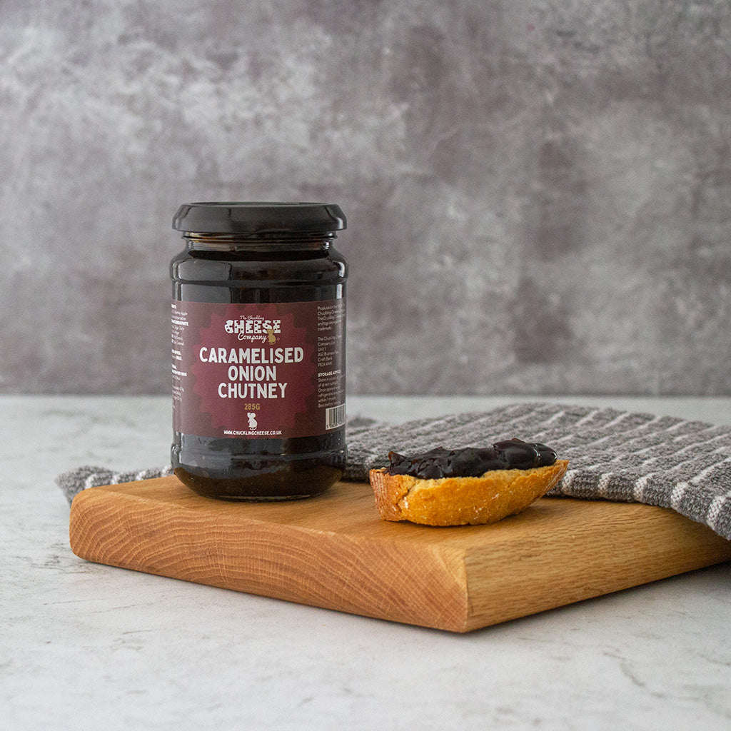 Chuckling Cheese Caramelised Onion Chutney jar with chutney-topped cracker on a wooden board