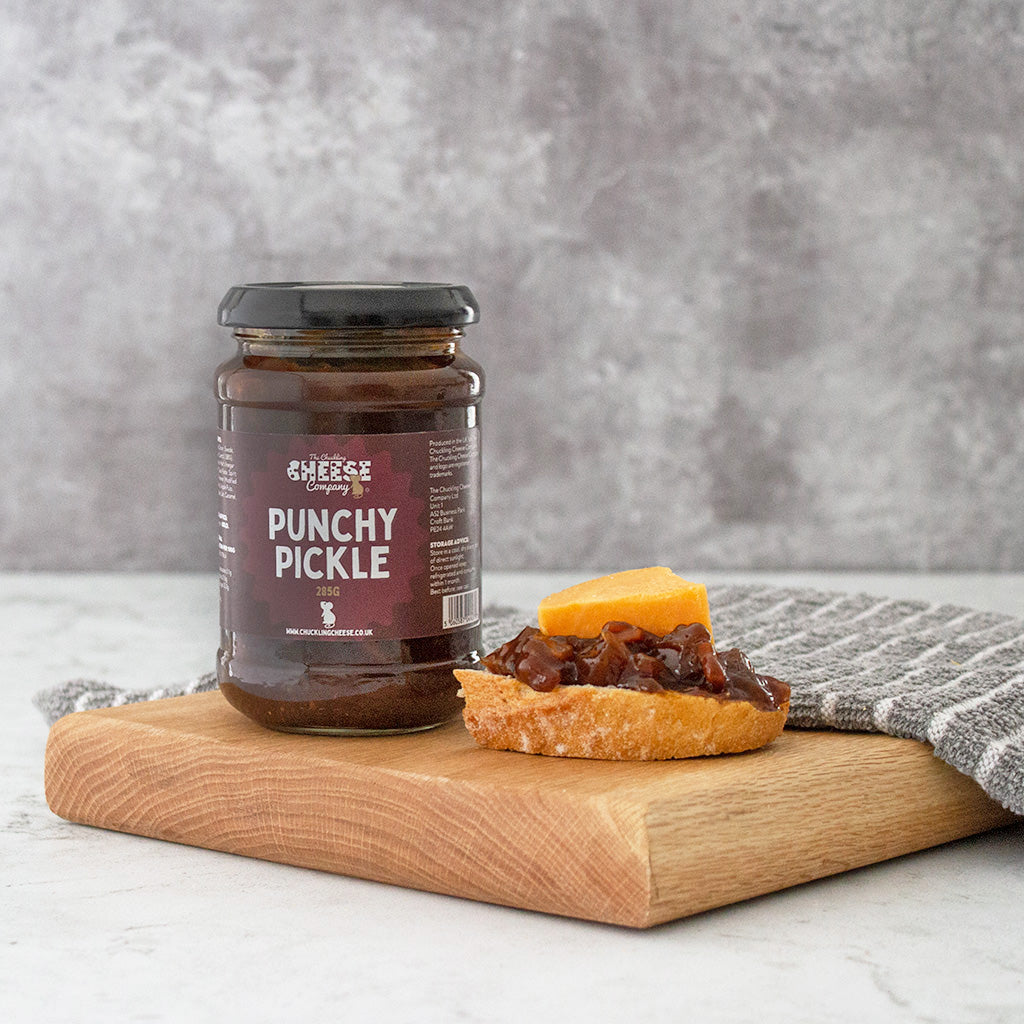 Chuckling Cheese Punchy Pickle jar with cheese on crackers on a wooden board