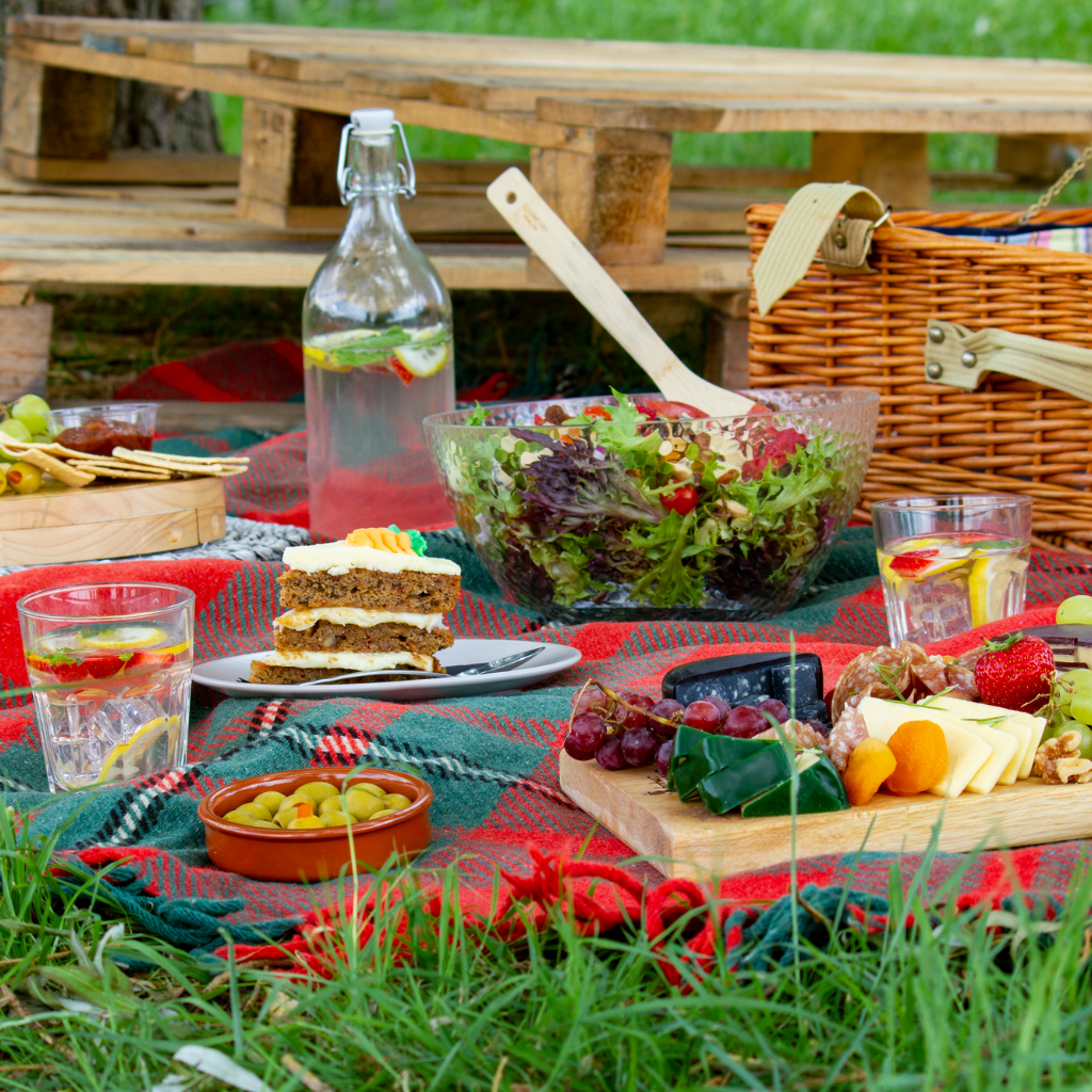 Outdoor picnic spread with cheese, fruit, salad and drinks for al fresco dining