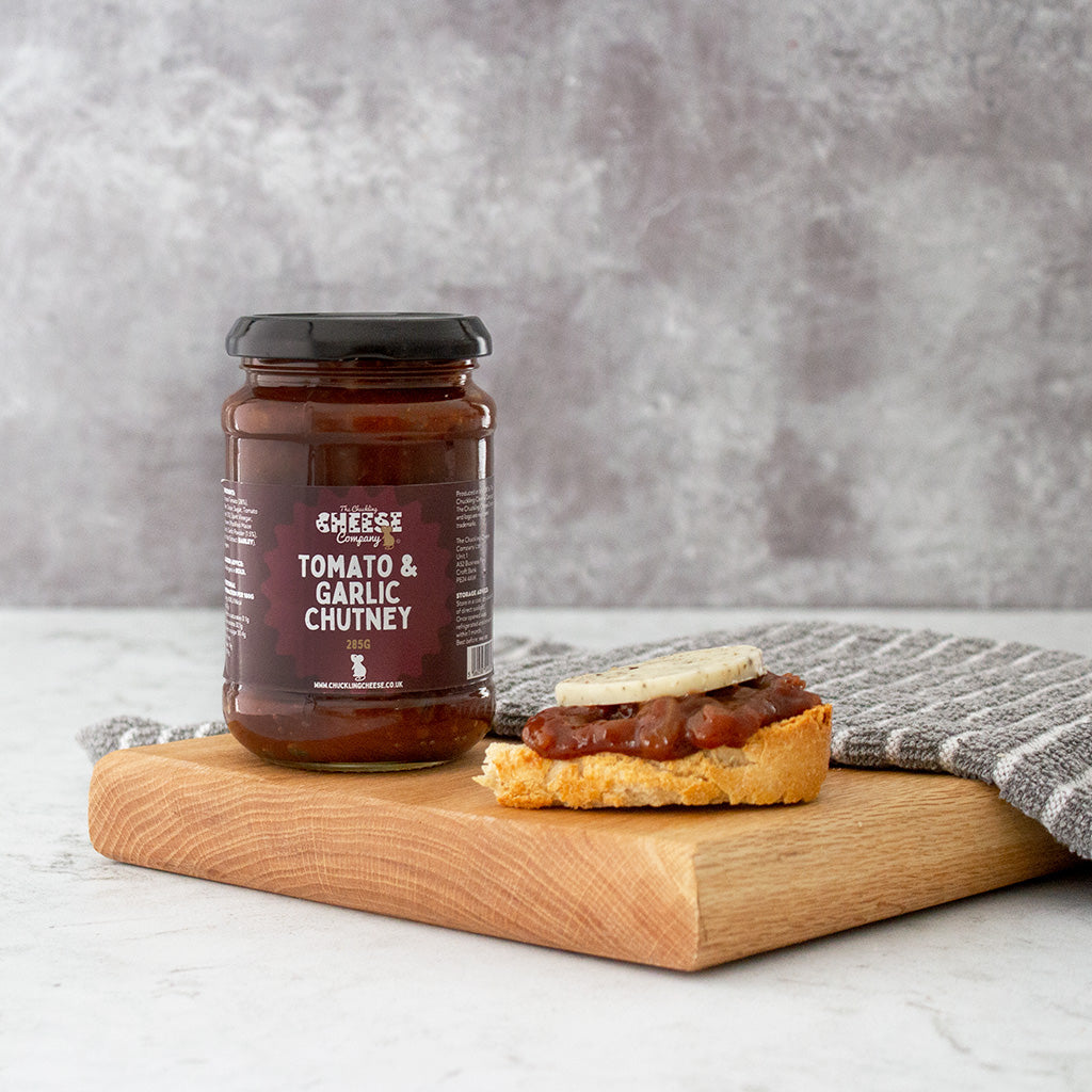 Chuckling Cheese Tomato & Garlic Chutney jar with cheese on crackers on a wooden board