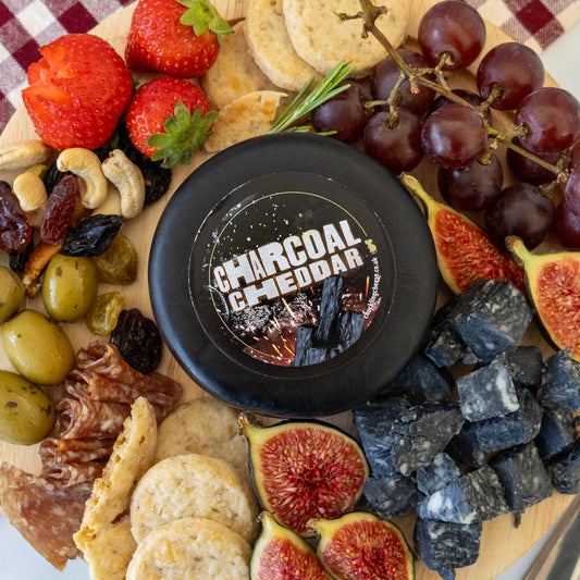 Halloween cheese platter with Charcoal Cheddar, crackers, grapes, figs, strawberries, olives, nuts and dark cheese cubes.