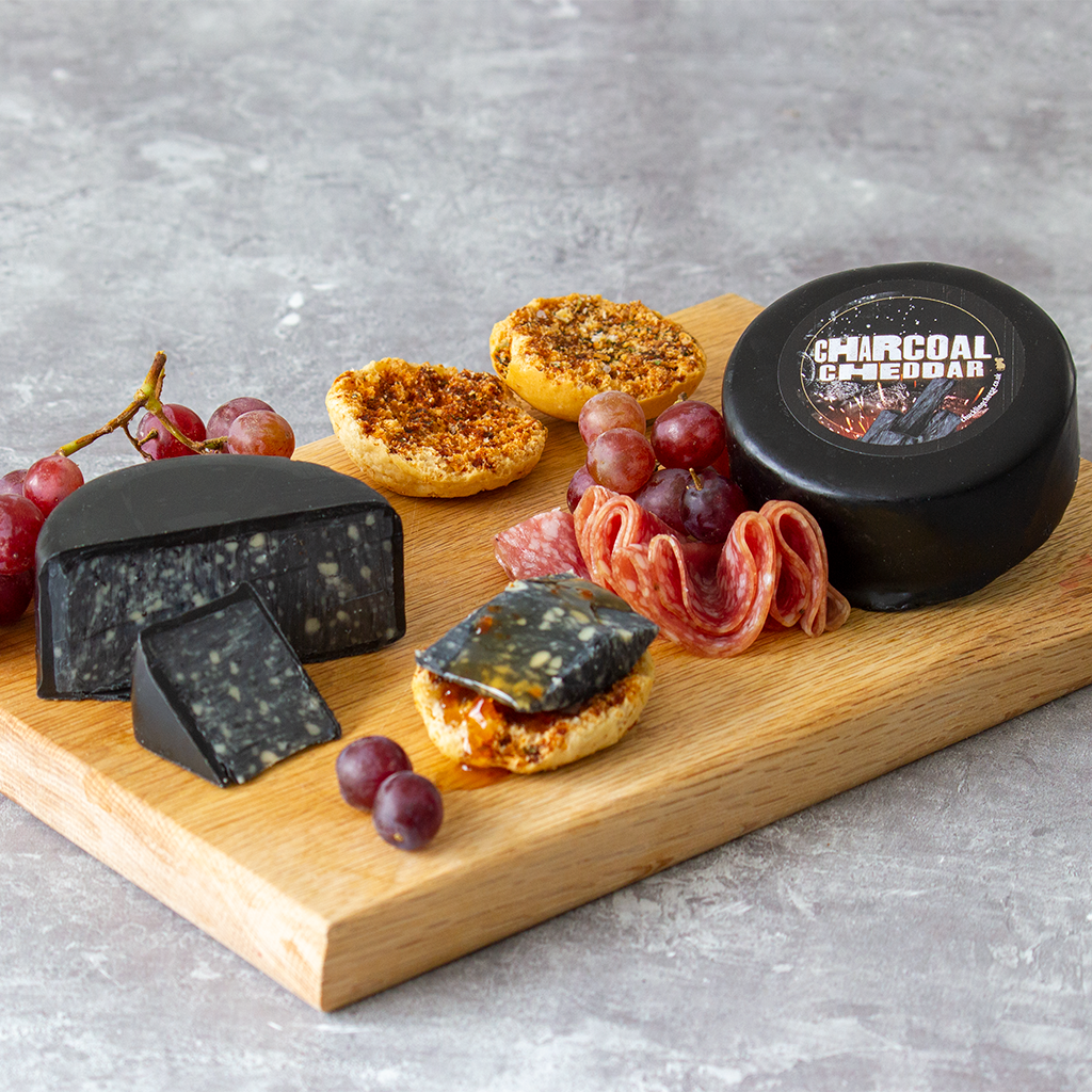 Chuckling Cheese Charcoal Cheddar Truckle with black cheese, grapes, charcuterie and crackers