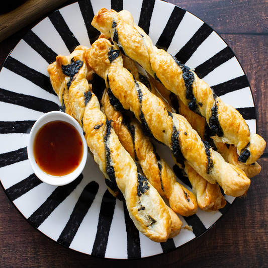 Golden puff pastry twists filled with black Charcoal Cheddar cheese and served with dipping sauce