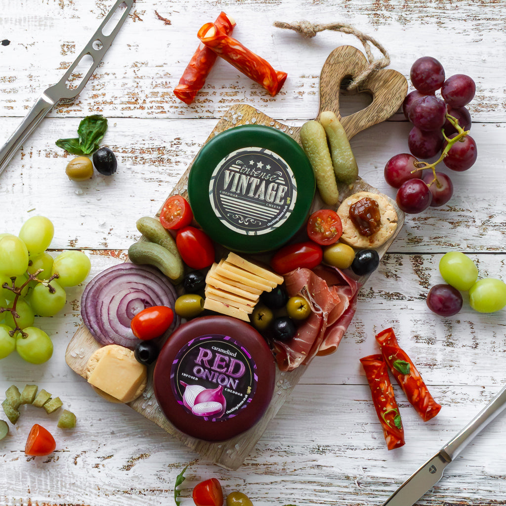 Chuckling Cheese cheeseboard with Vintage and Red Onion cheddar truckles, grapes, crackers and charcuterie