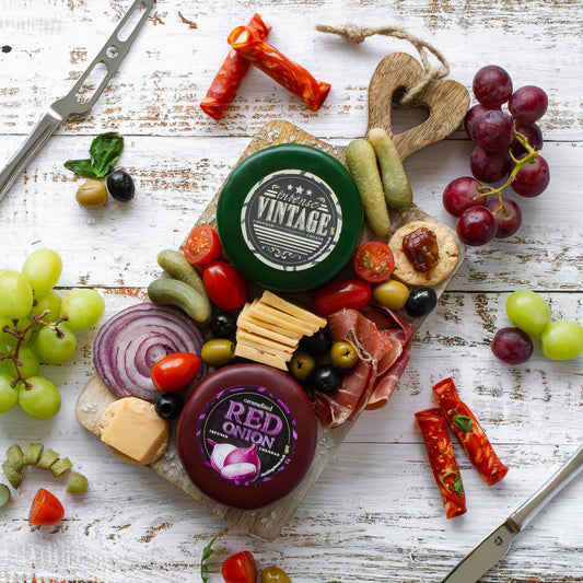 Chuckling Cheese cheeseboard with Vintage and Red Onion cheddar truckles, grapes, crackers and charcuterie