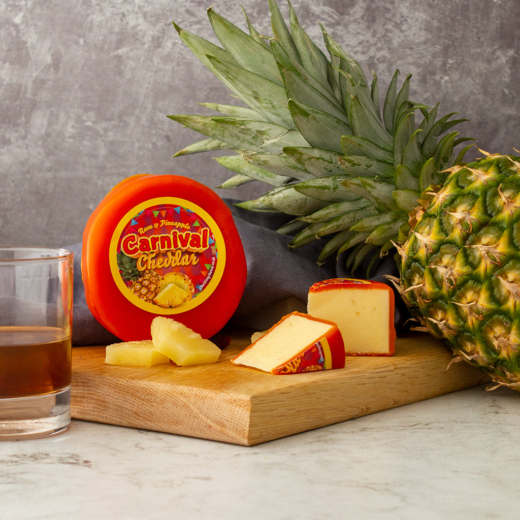 Chuckling Cheese Rum & Pineapple Carnival Cheddar with pineapple, rum glass and sliced cheese