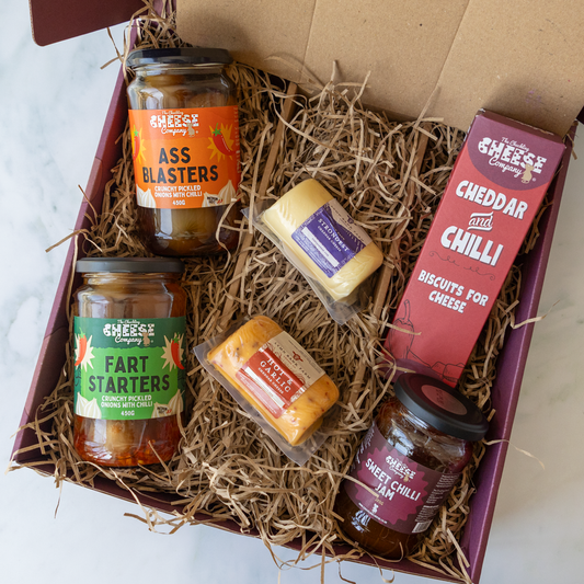 Chuckling Cheese gift hamper with two cheese barrels, cheddar and chilli biscuits and three jars of savoury accompaniments in a straw-lined box