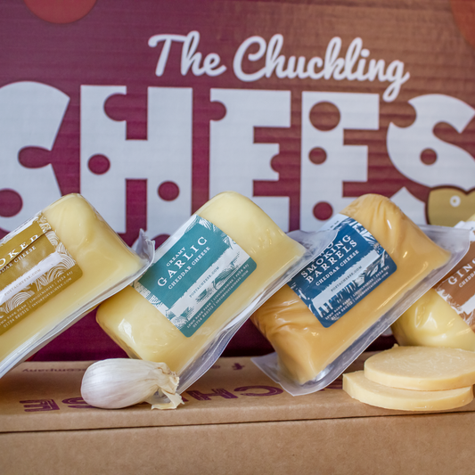 Assorted flavoured cheese wedges from The Chuckling Cheese Company displayed with garlic and sliced cheese.