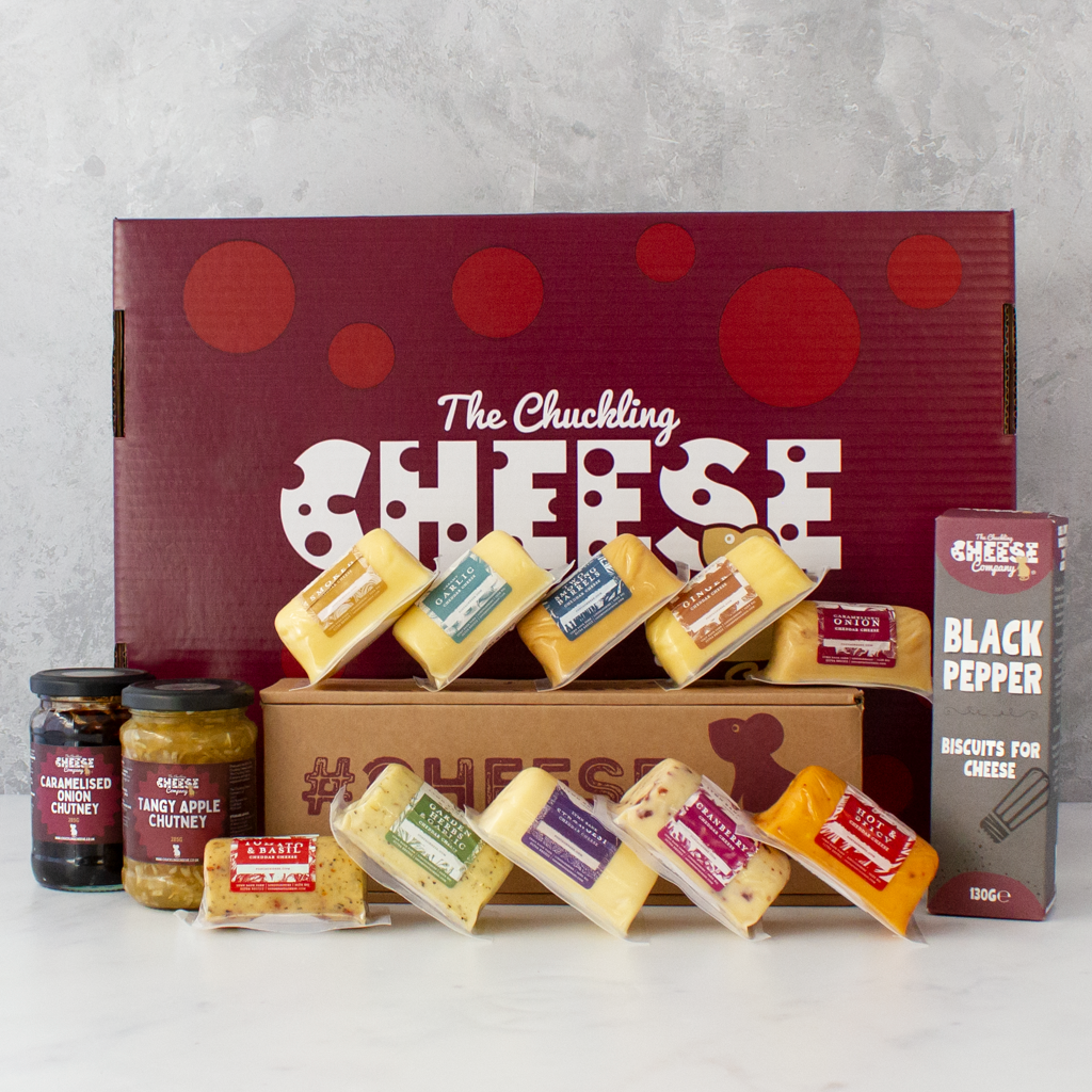 Chuckling Cheese gift hamper with assorted cheddar barrels, chutney jars and black pepper biscuits beside a branded gift box