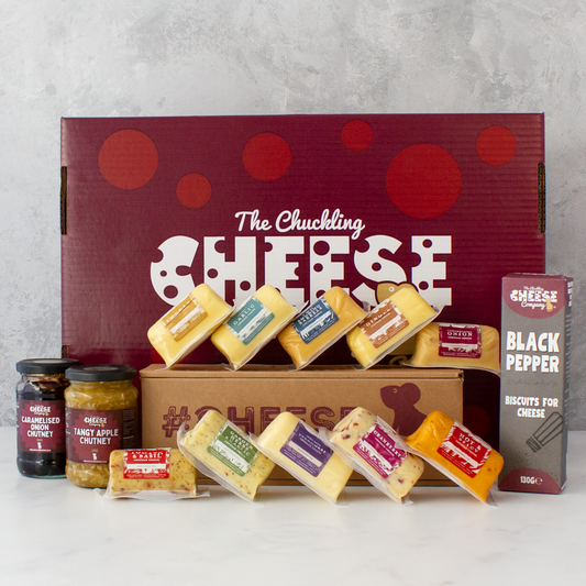 Chuckling Cheese gift hamper with assorted cheddar barrels, chutney jars and black pepper biscuits beside a branded gift box