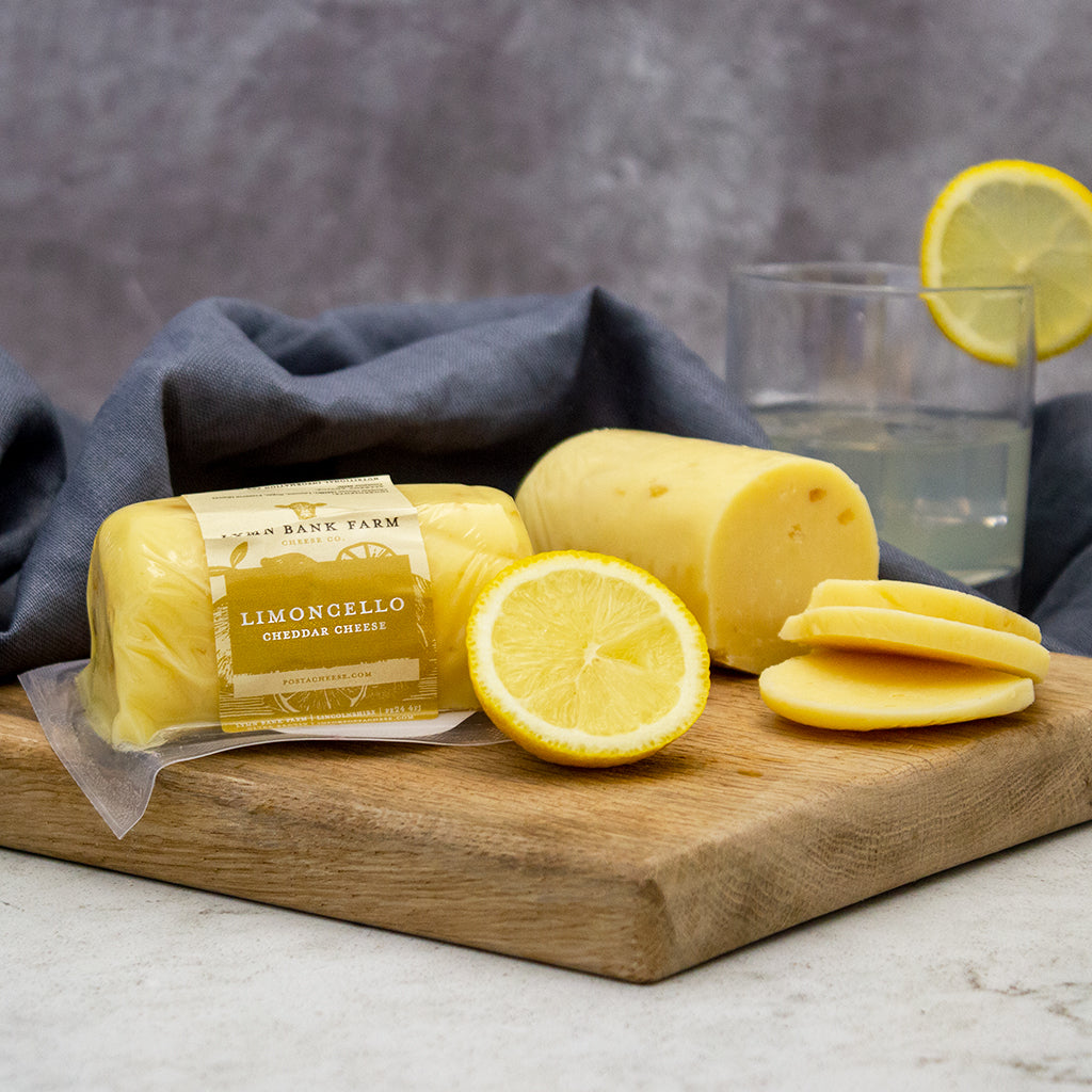 Chuckling Cheese Limoncello Cheddar Barrel with lemon slices and cheese on a wooden board