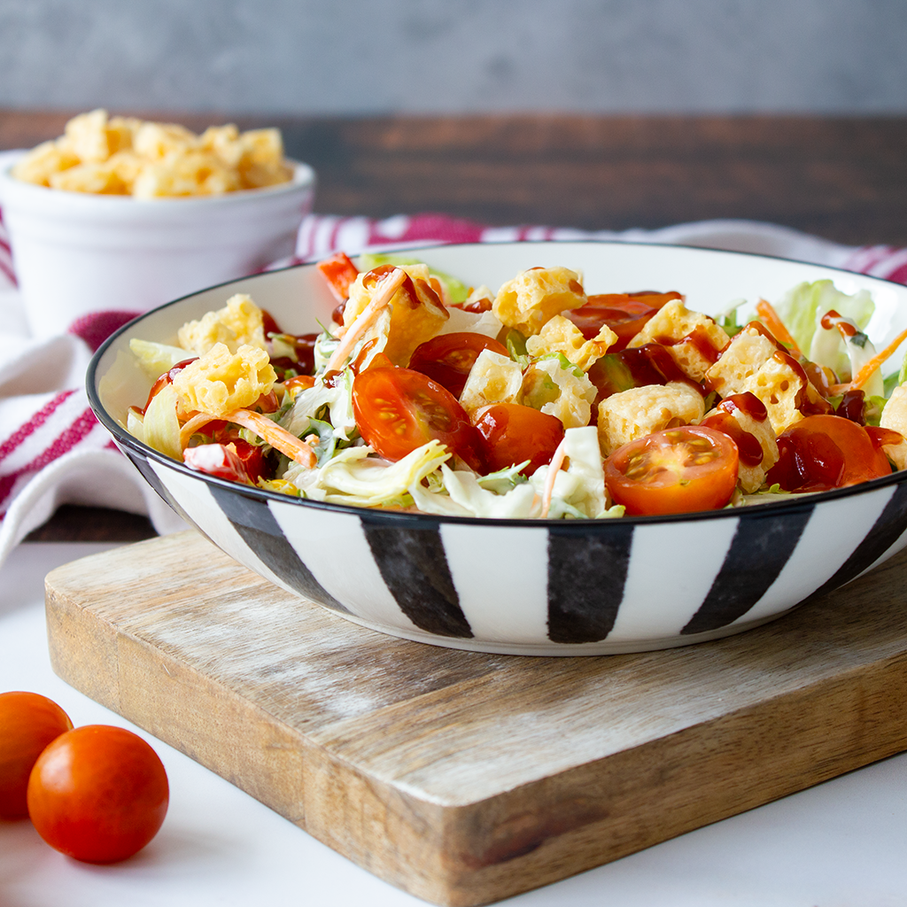 Summer salad topped with Munchie’s Crunchies, cherry tomatoes and a drizzle of sauce