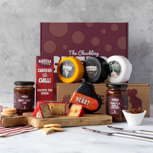 Chuckling Cheese gift hamper with assorted cheese truckles, cheddar and chilli biscuits, chutneys and sliced cheese on a wooden board