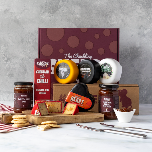 Chuckling Cheese gift hamper with assorted cheese truckles, cheddar and chilli biscuits, chutneys and sliced cheese on a wooden board