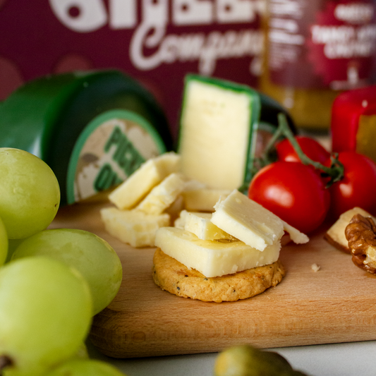 Cheese and crackers with grapes, tomatoes and a green waxed cheese truckle
