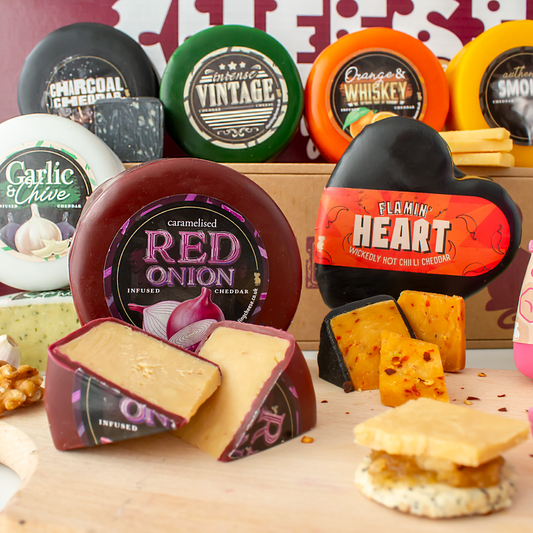 Selection of waxed cheese truckles with sliced cheese, crackers and chutney