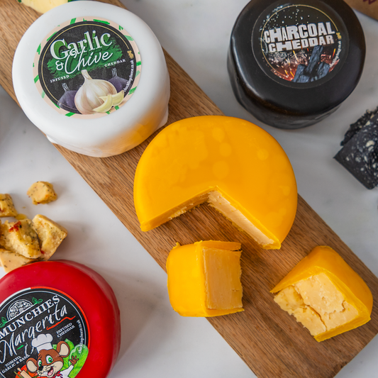 Assorted cheese truckles including Garlic & Chive, Charcoal Cheddar and Punchy Margherita, displayed on a wooden serving board.