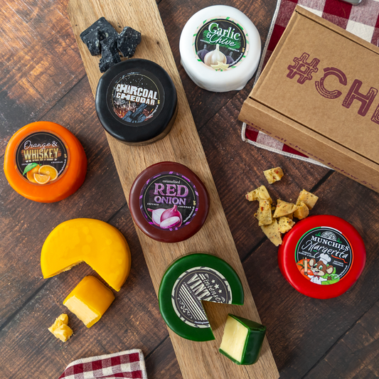 Assorted Chuckling Cheese truckles from a rainbow cheese gift box arranged on a wooden board