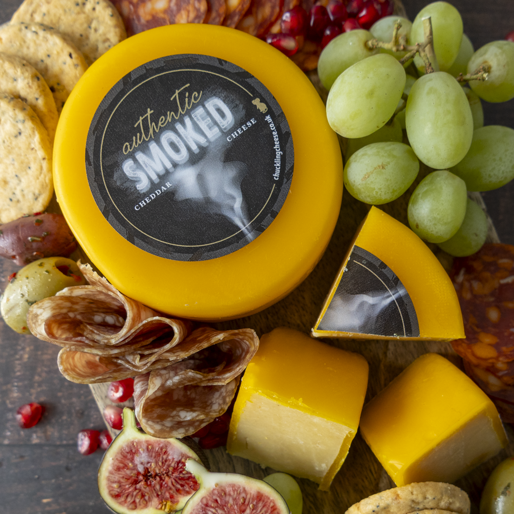Chuckling Cheese Smoked Cheddar Truckle with grapes, crackers, cured meat, figs and sliced cheese