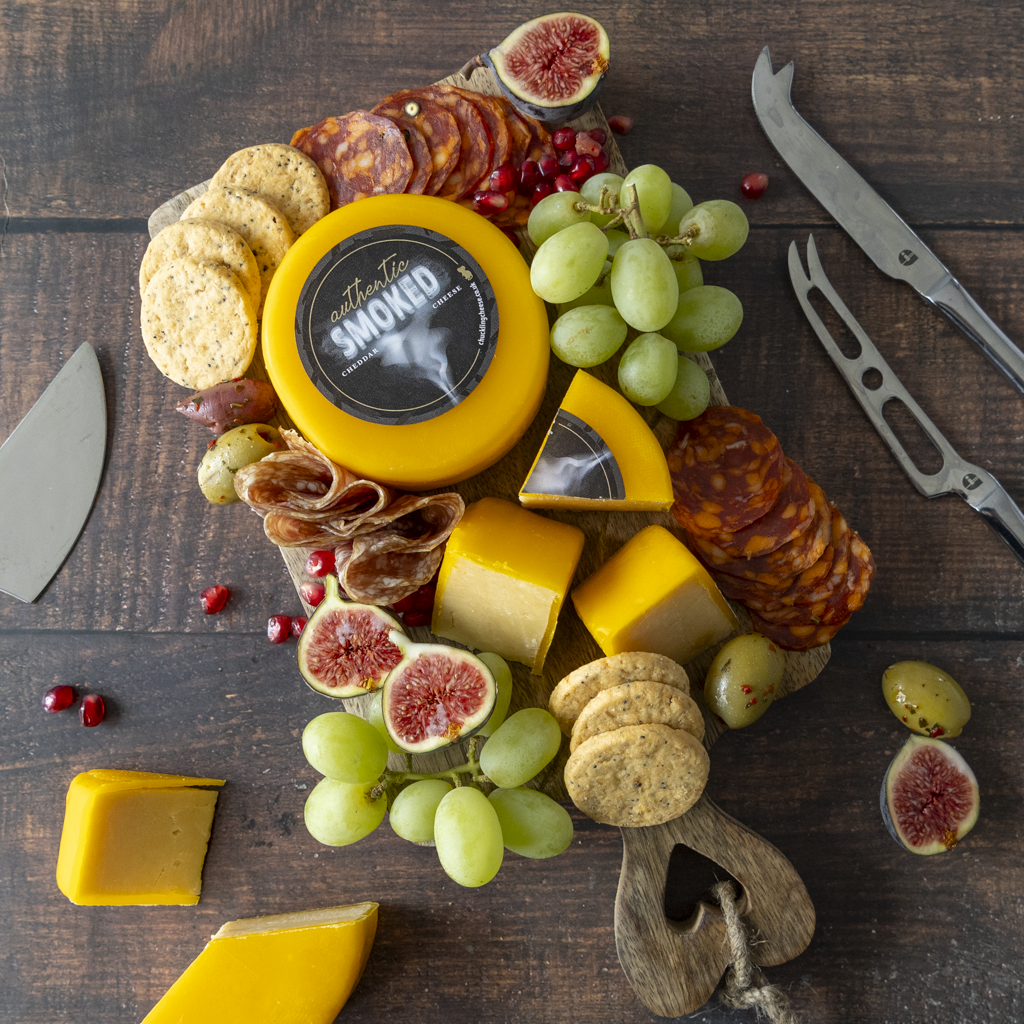 June Cheese of the Month Authentic Smoked Cheddar Cheese served on a summer cheeseboard with crackers, grapes and chutney-style pairings
