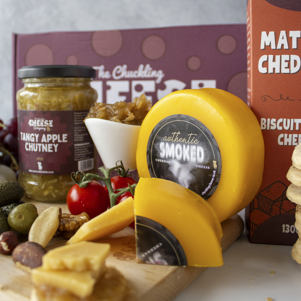 Smoked cheese truckle on a cheeseboard with crackers, chutney, olives and tomatoes