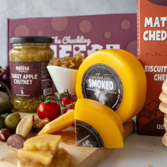 Smoked cheese truckle on a cheeseboard with crackers, chutney, olives and tomatoes