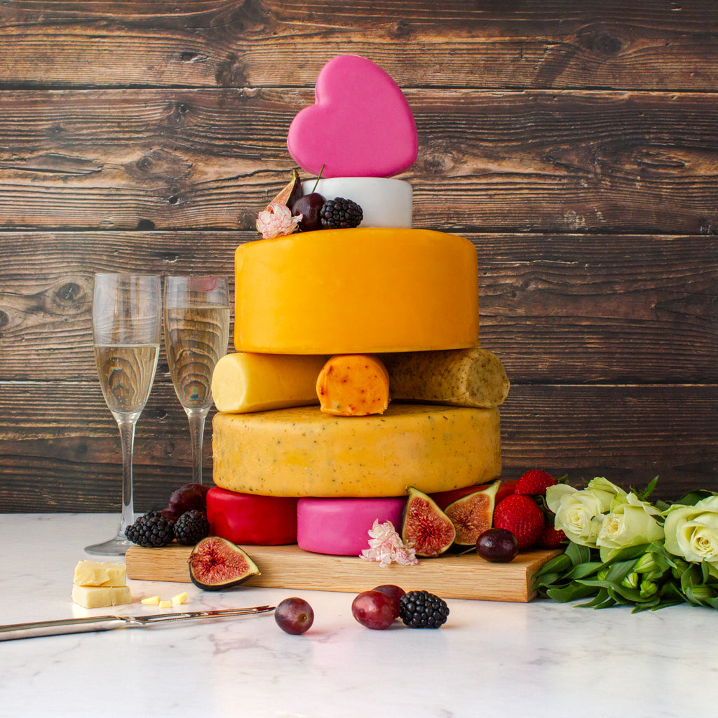 Chuckling Cheese celebration cheese cake with stacked cheeses, pink heart topper, fruit and champagne