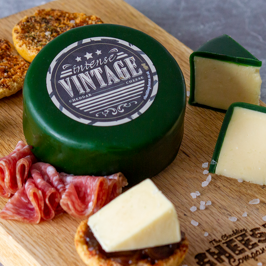 Chuckling Cheese Vintage Cheddar Truckle with grapes, charcuterie, crackers and sliced cheese