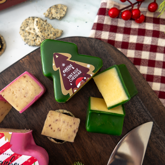 Festive cheese board with Christmas-shaped Vintage Cheddar, assorted cheese pieces and crackers on a wooden serving board.