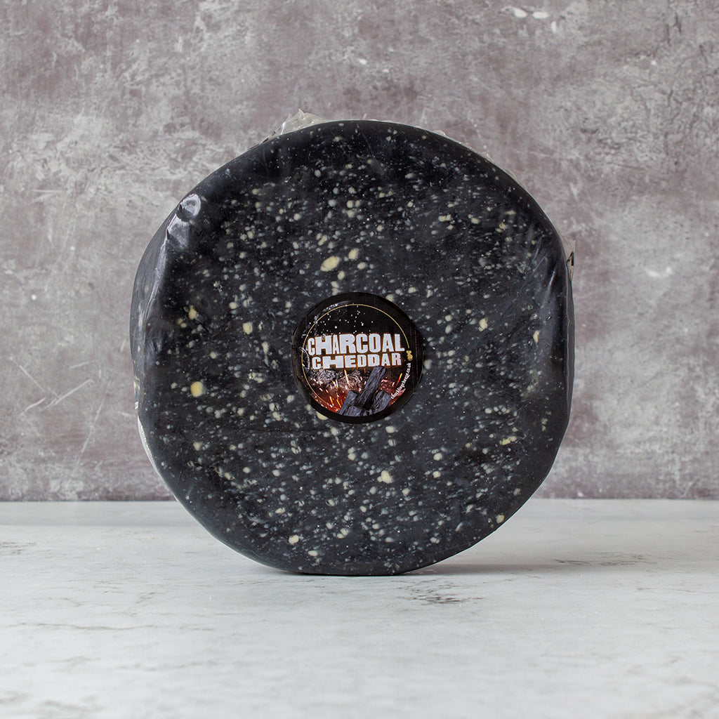 Chuckling Cheese Charcoal Cheddar Wheel 2.25kg with a brand logo on a gray background