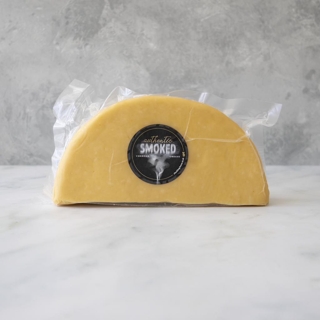 Half wheel of apple moked cheese with a label on a white surface