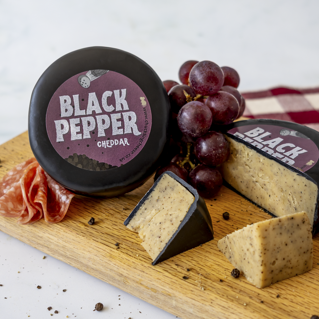 Chuckling Cheese Black Pepper Cheddar Truckle with grapes, charcuterie and cheese wedges