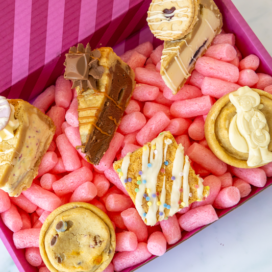 A boxed assortment of assorted cookies and chocolate treats arranged in pink cookie box.