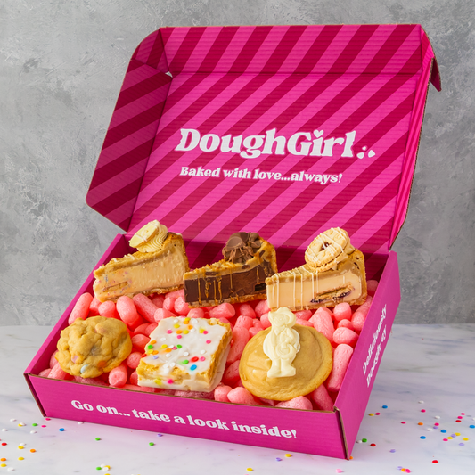 Open pink DoughGirl Happy Birthday Bundle box with various mini pies on a gray background