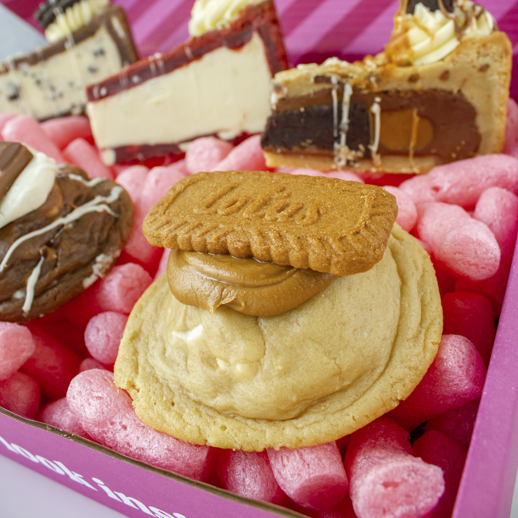 Close-up of a Biscoff Deluxe Cookie with a pink box in the background.