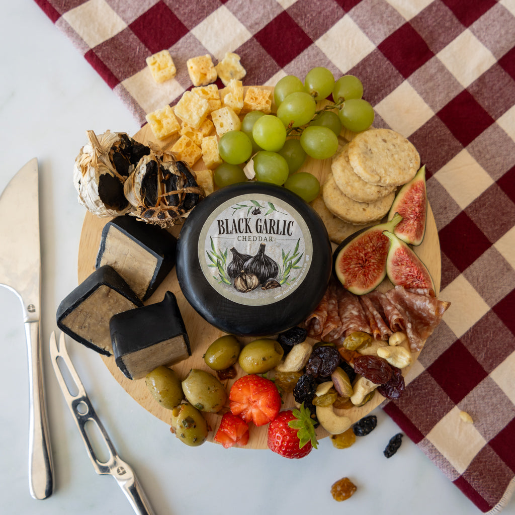Chuckling Cheese Black Garlic Cheddar Truckle with black garlic, grapes, figs, crackers and cheese slices