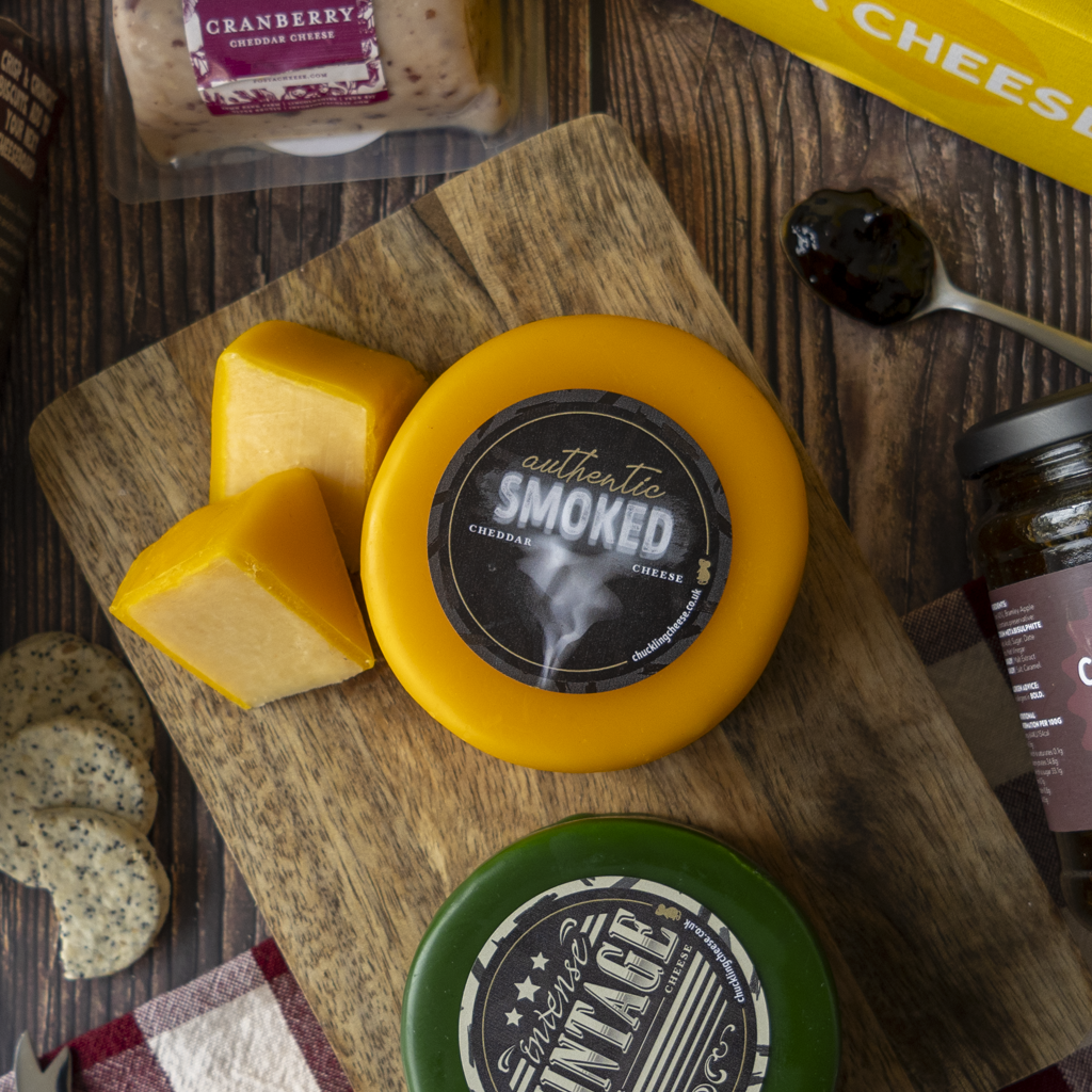 Authentic Smoked Cheddar with Intense Vintage Cheddar, cheese cubes and crackers on a wooden board.