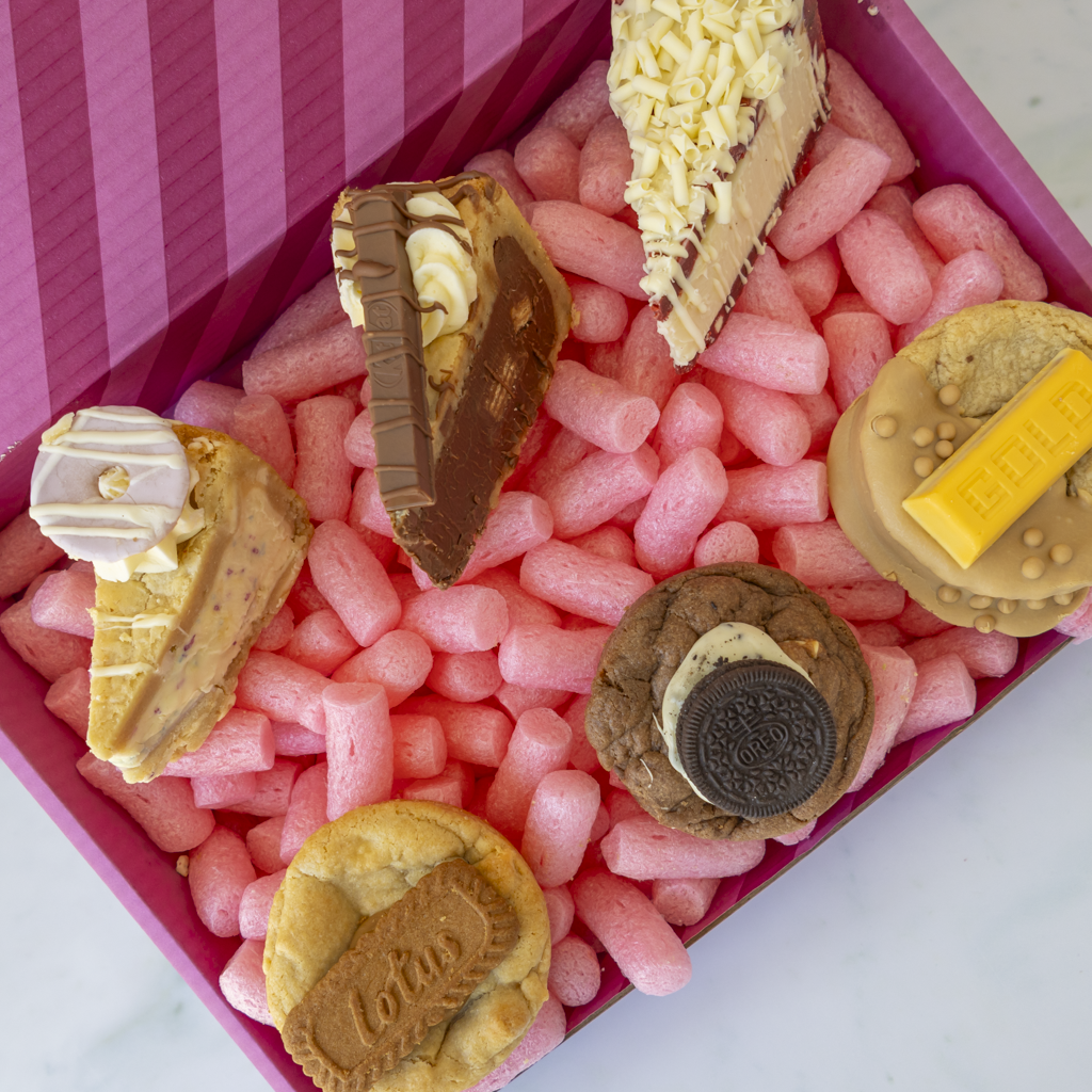 Assorted celebration cookies and cookie pie slices inside a pink DoughGirl gift box