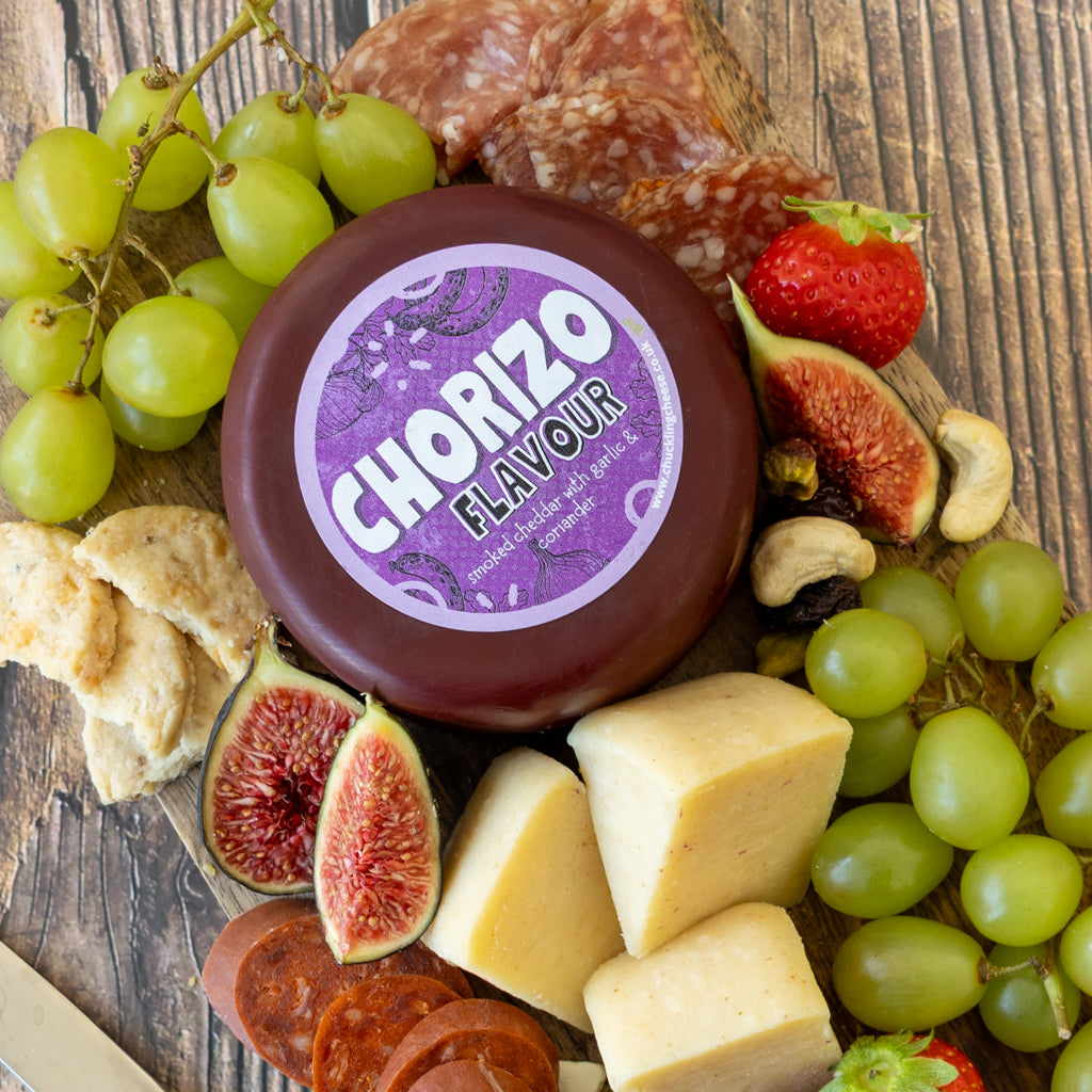 Chuckling Cheese Chorizo Cheddar Truckle with grapes, chorizo slices and cheddar on a wooden board