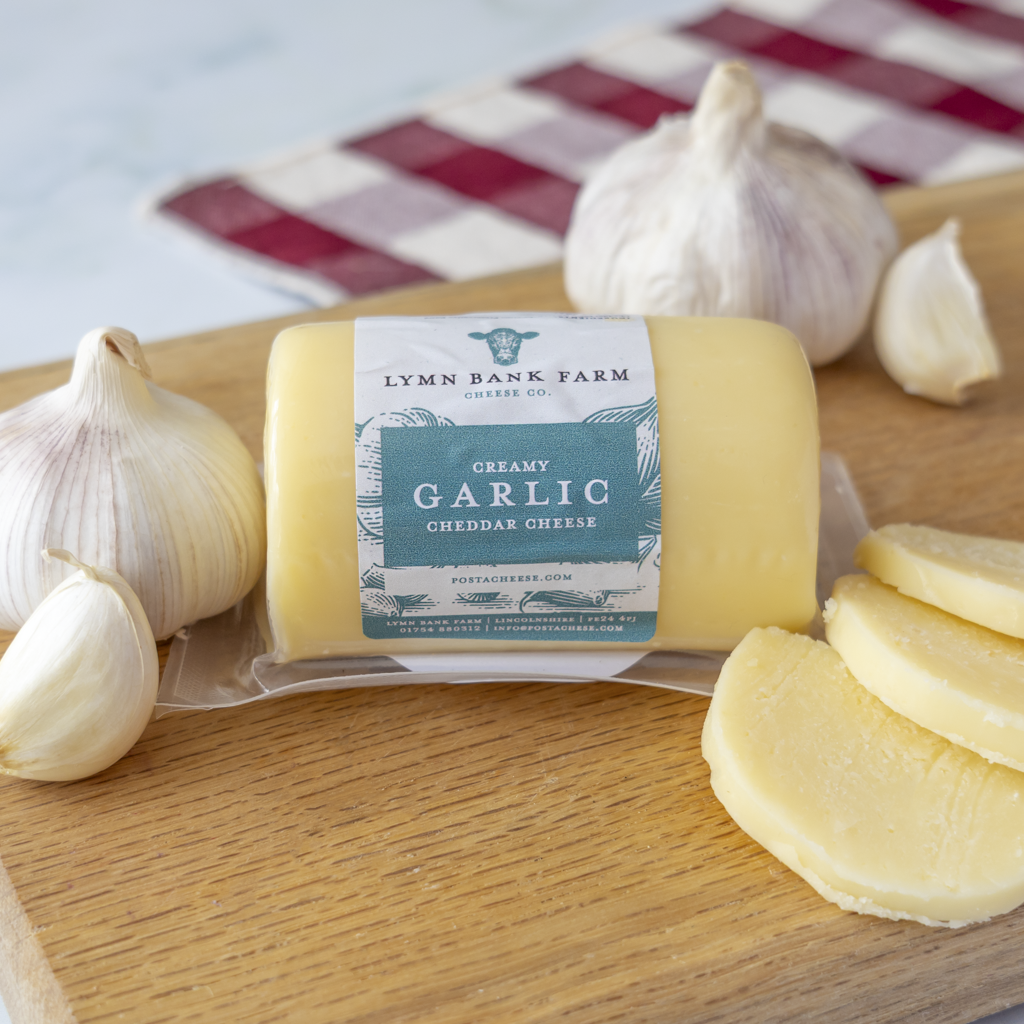 Chuckling Cheese Garlic Cheddar Barrel with garlic bulbs and sliced cheddar
