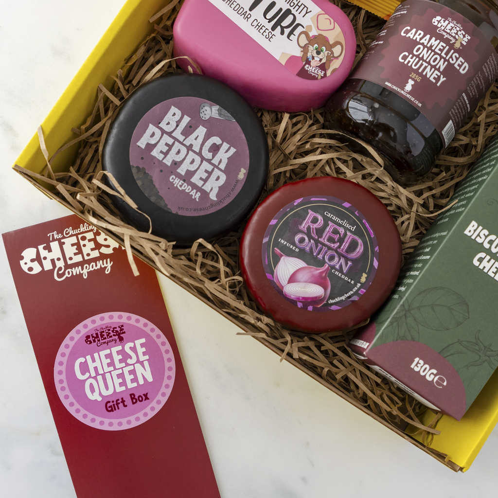 Collection of cheese and condiment products in a Cheease Queen gift box with visible branding.