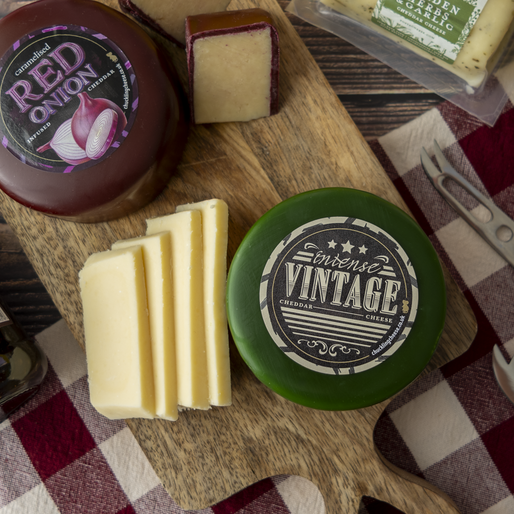 Close-up of Intense Vintage Cheddar with sliced cheese and Caramelised Red Onion Cheddar on a wooden board.