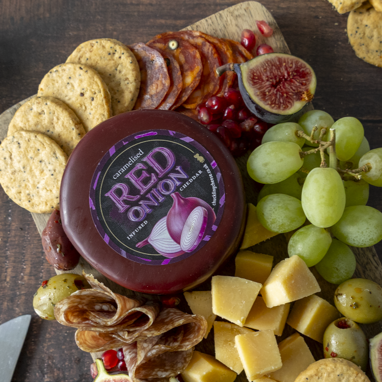 Caramelised Red Onion Cheddar Truckle on a cheeseboard with grapes and savoury snacks
