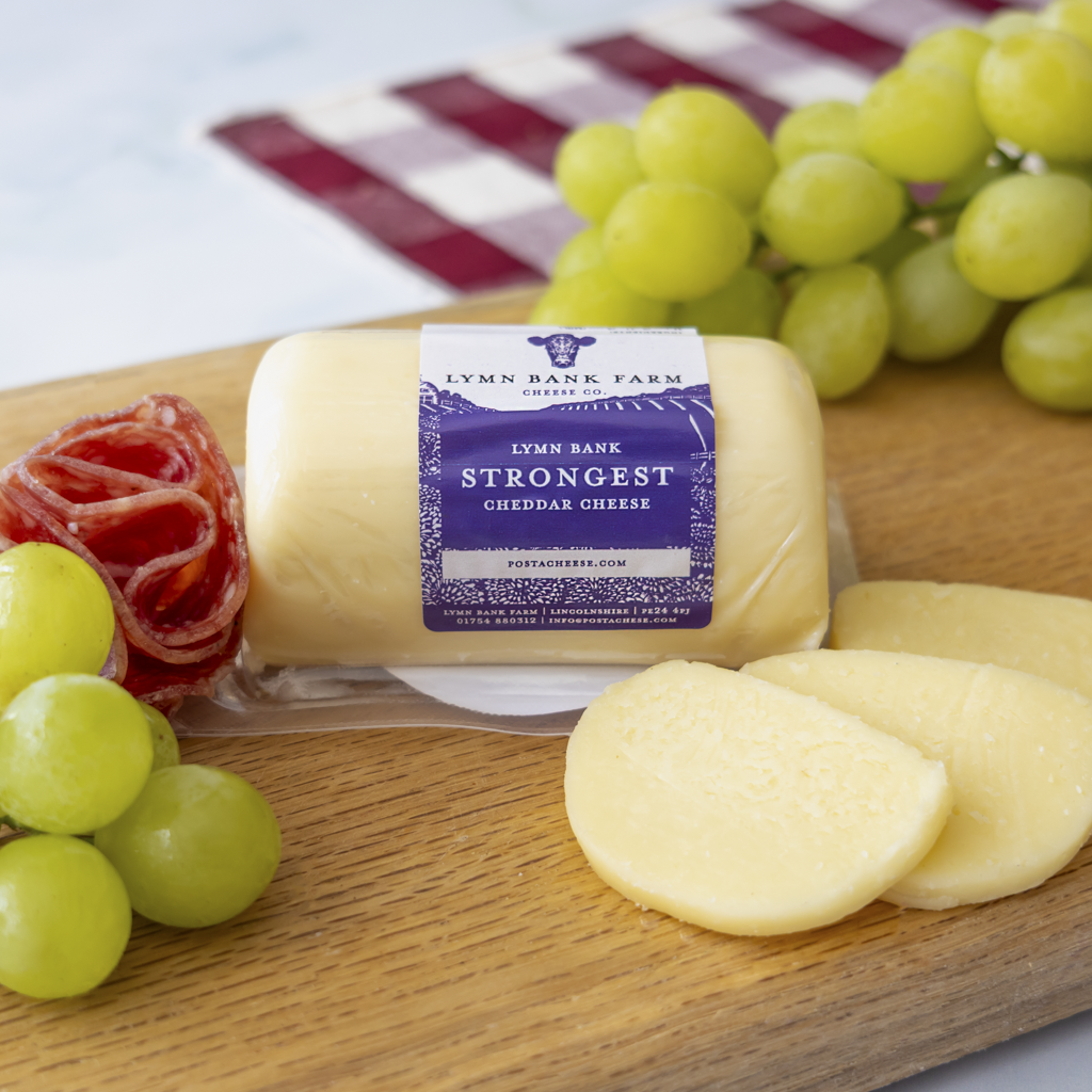 Chuckling Cheese Strongest Cheddar Barrel with grapes, charcuterie and cheese slices