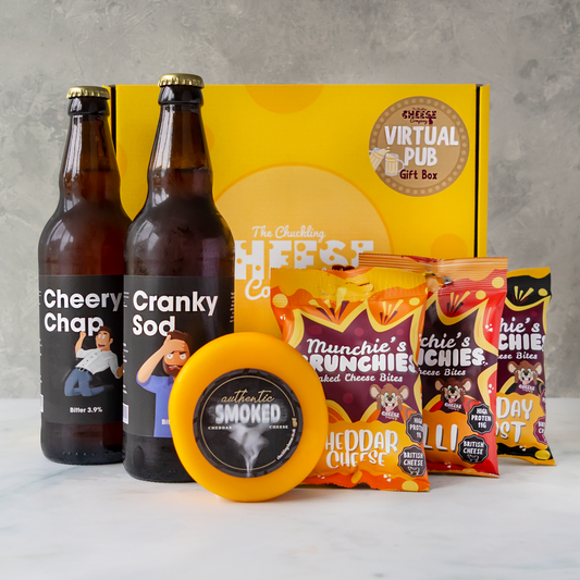 A Virtual Pub Gift Box with a yellow branded box, 2 bottles of beer, an authentic smoked cheese truckle and 3 packs of baked cheese bites against a grey background