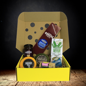 The Classic Cheeseboard Blue Sticker Gift Box which includes a smoked truckle, vintage truckle, cranberry barrel, a wedge of yorkshire blue cheese, a box of crackers and a jar of chutney.